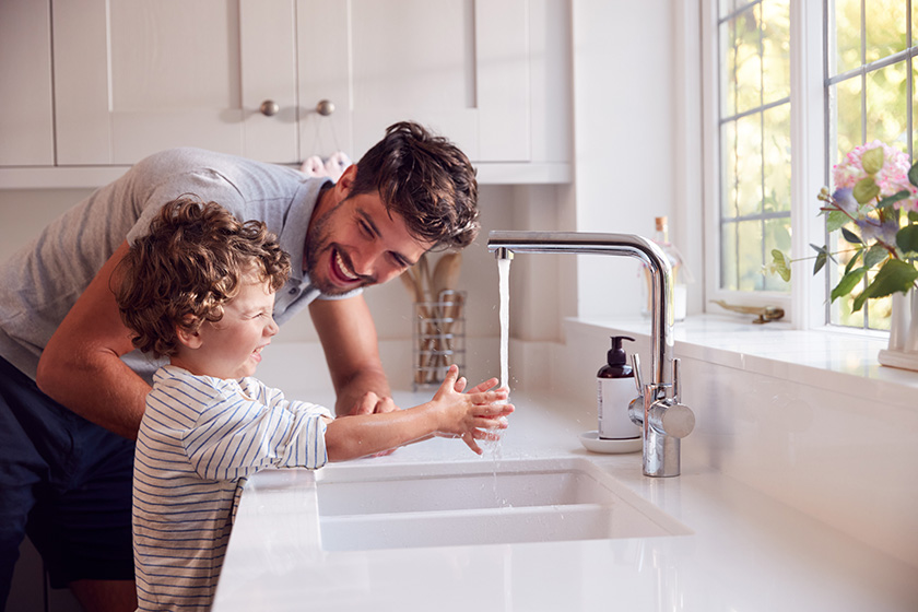 father and son at kitchen sink with running water