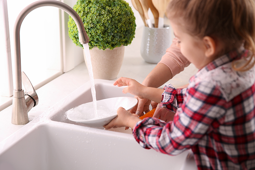 child washing dishes at the sink